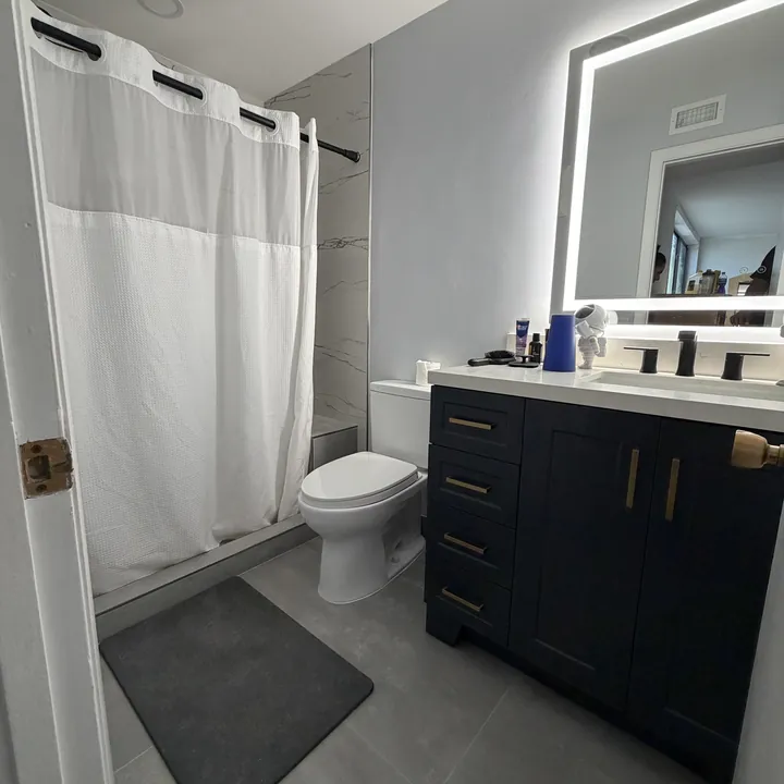 Baño al terminar, con mueble oscuro, espejo iluminado y piso despejado.